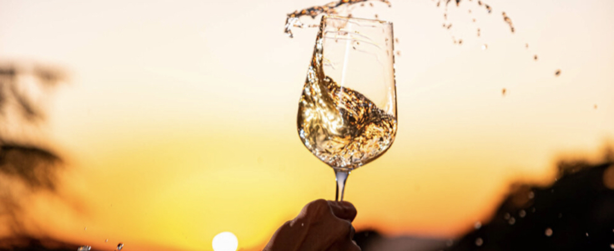 A glass of white wine swirling against the sunset